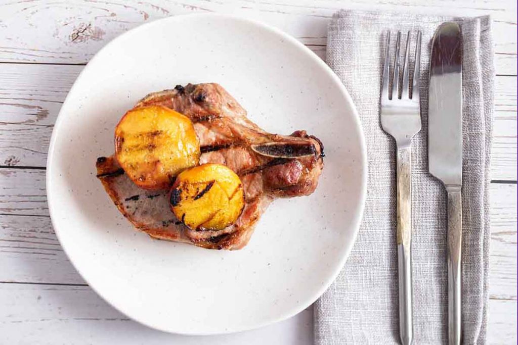 plate of grilled pork chop with peaches